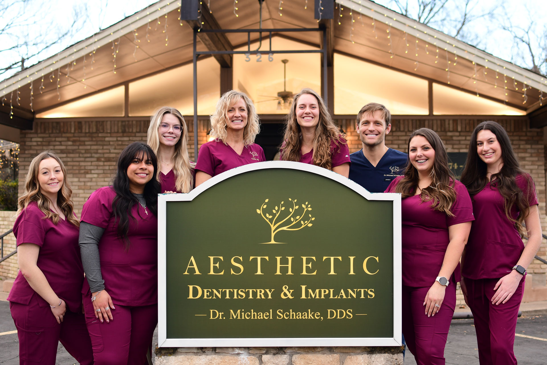 Dental team standing behind Aesthetic Dentistry & Implants sign in Weatherford, TX